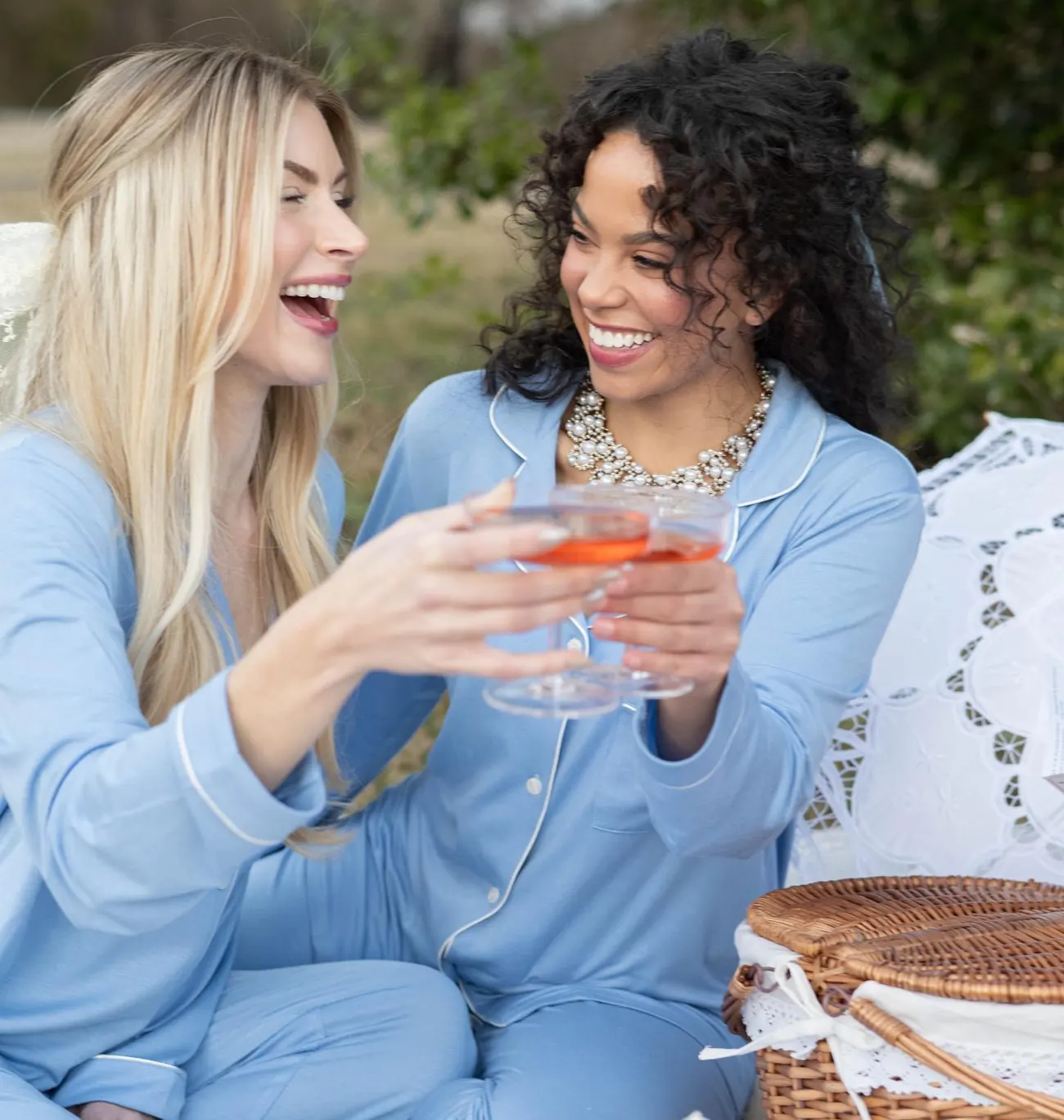 Two friends in matching blue In My Sundays loungewear raising glasses