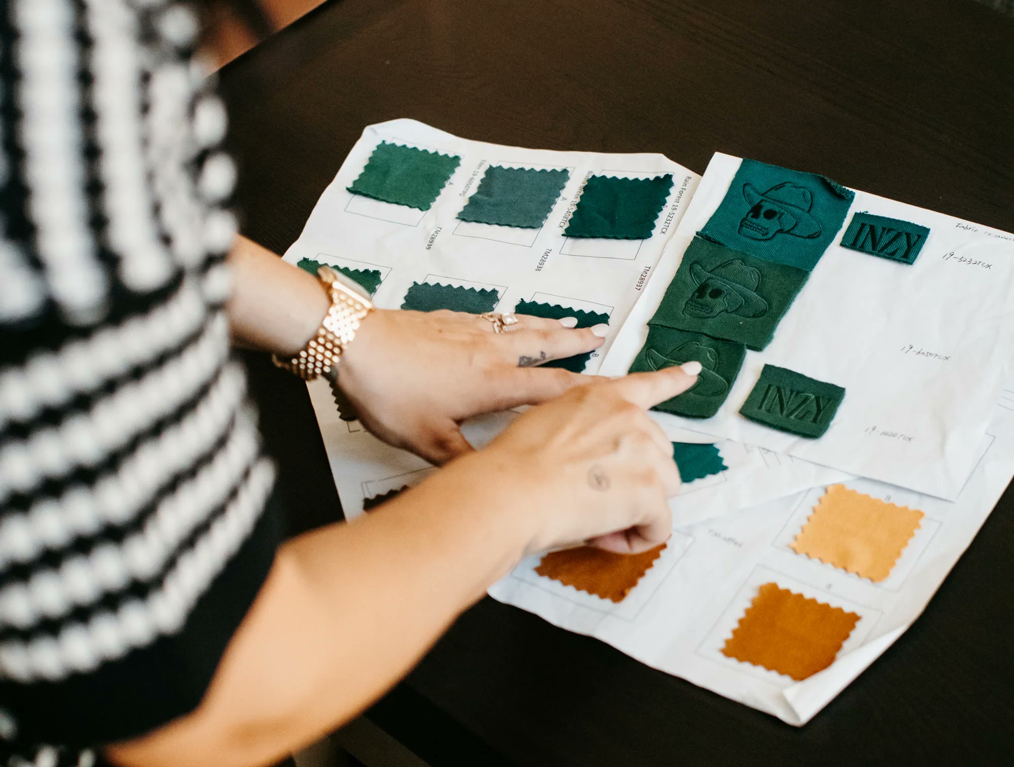 Hands reviewing fabric swatches and embroidered Inzy logo samples