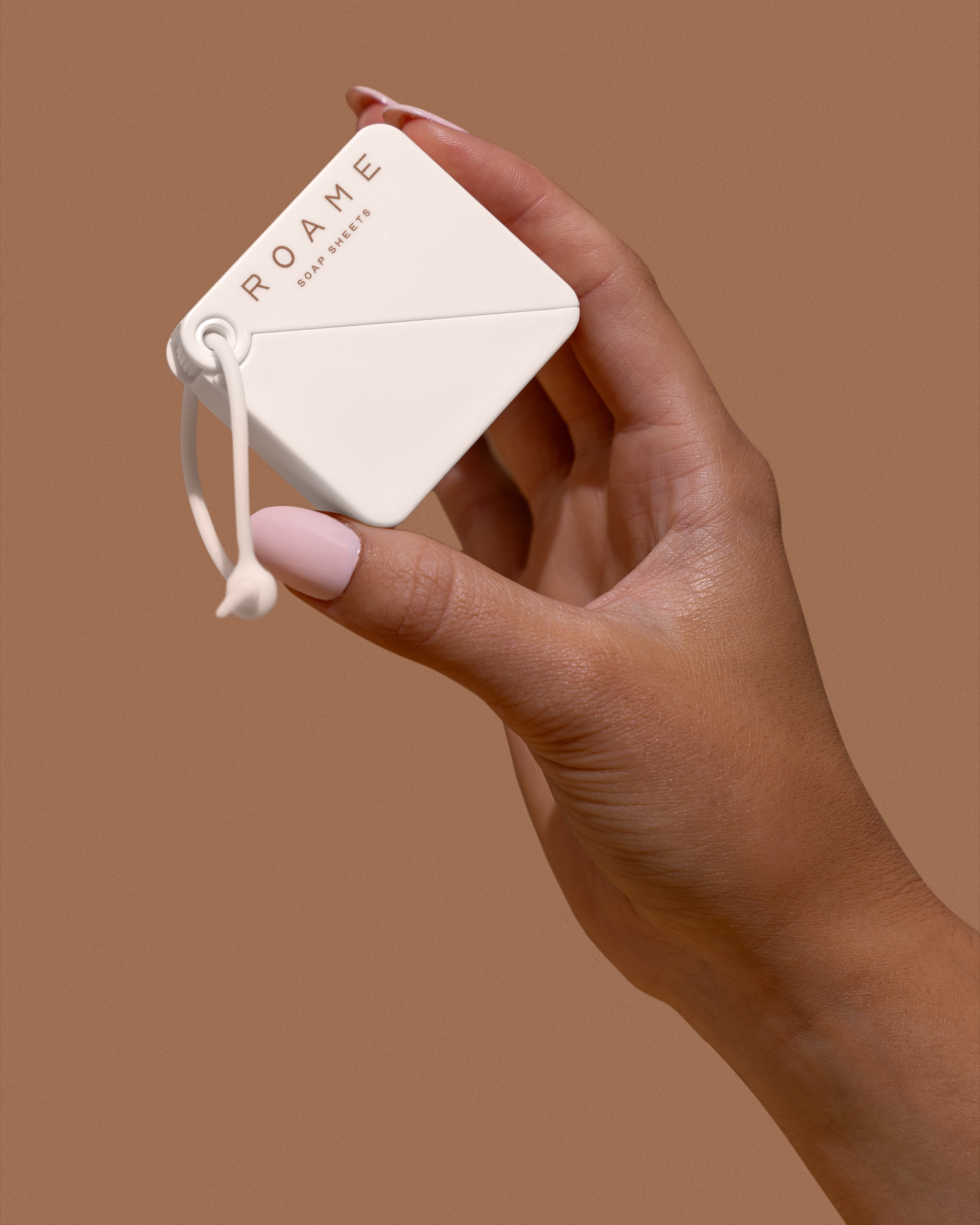 A hand holding a ROAME soap sheet case