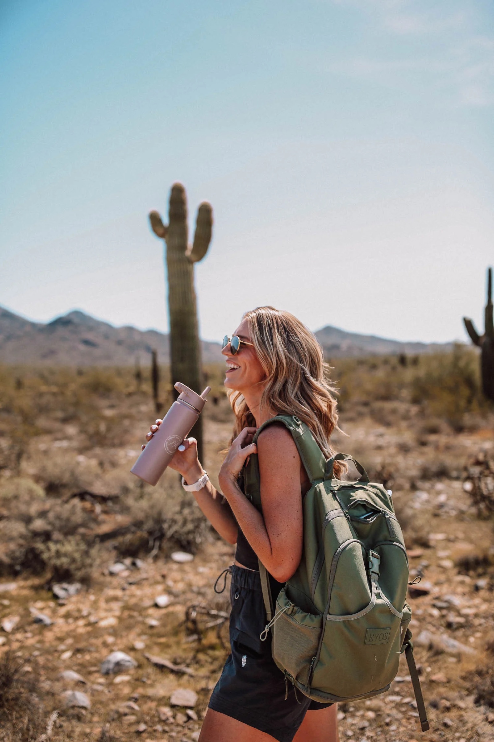 A hiker drinking from a bottle on a desert trail