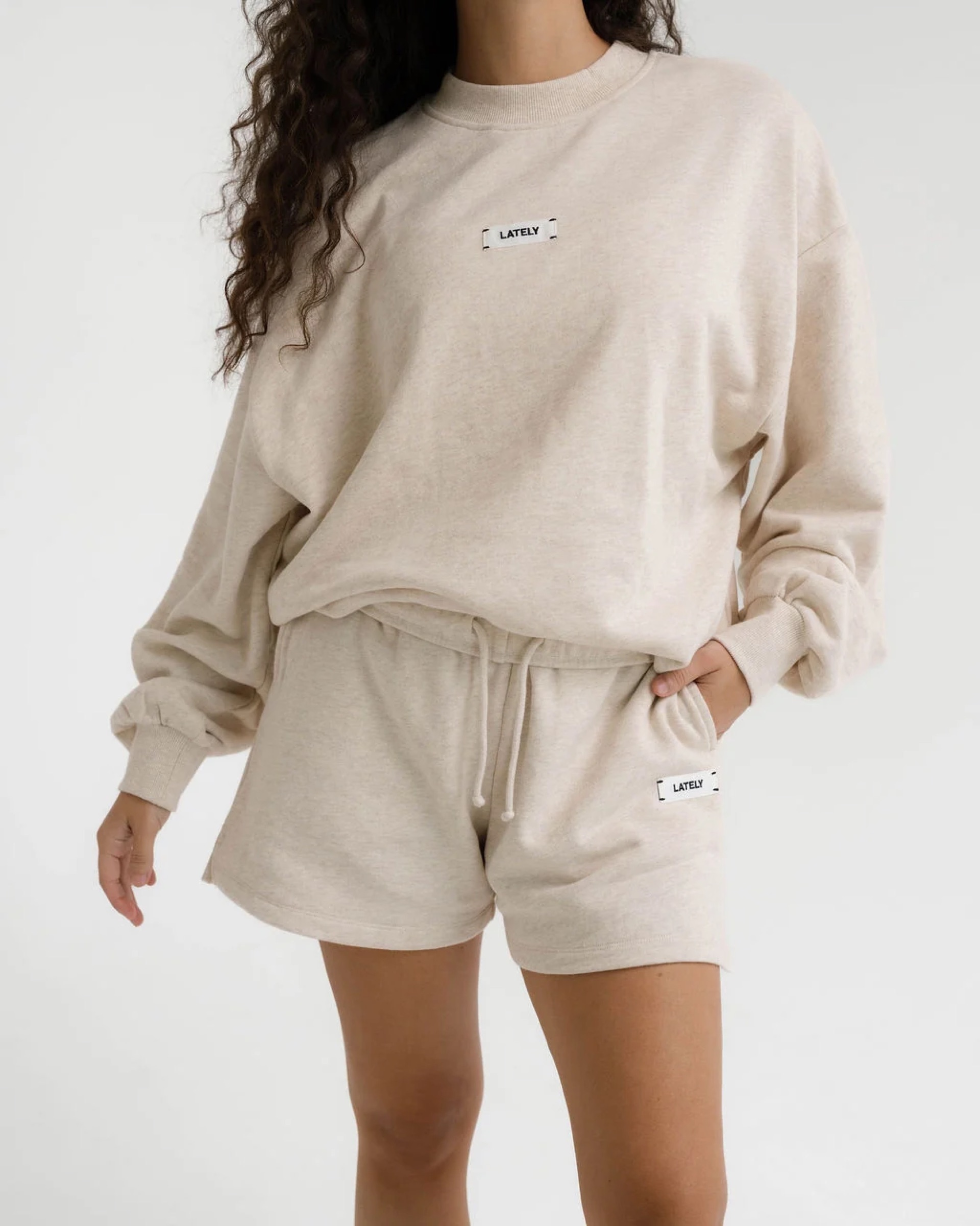 A model wearing a cream sweatshirt and matching shorts