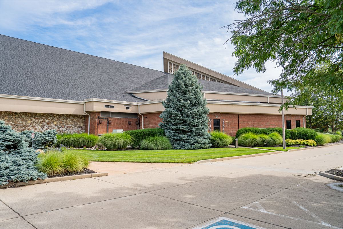 A church campus with trimmed foundation shrub beds and an evergreen along the entrance drive
