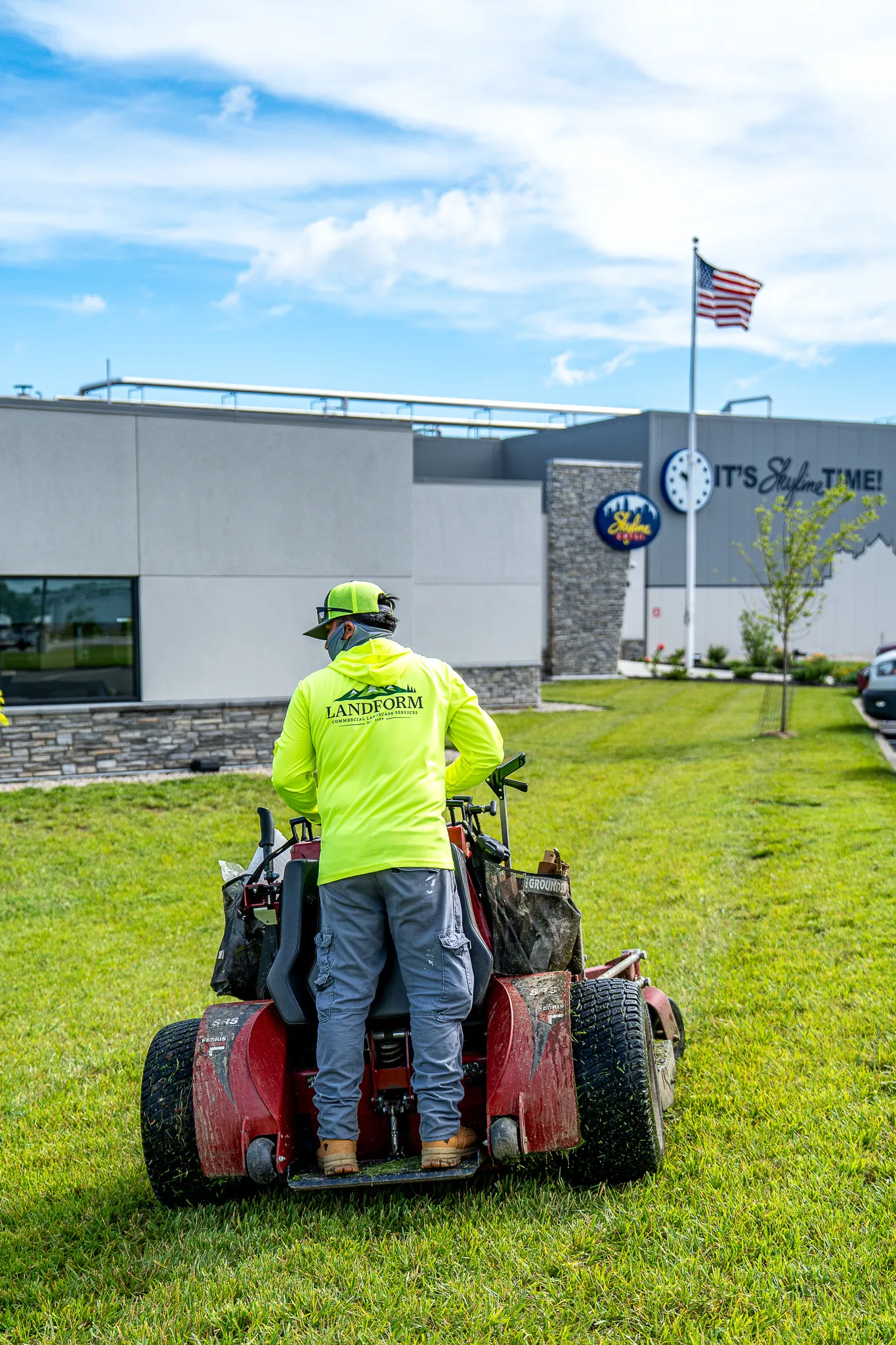 A Landform crew member in branded hi-vis mowing a commercial property lawn