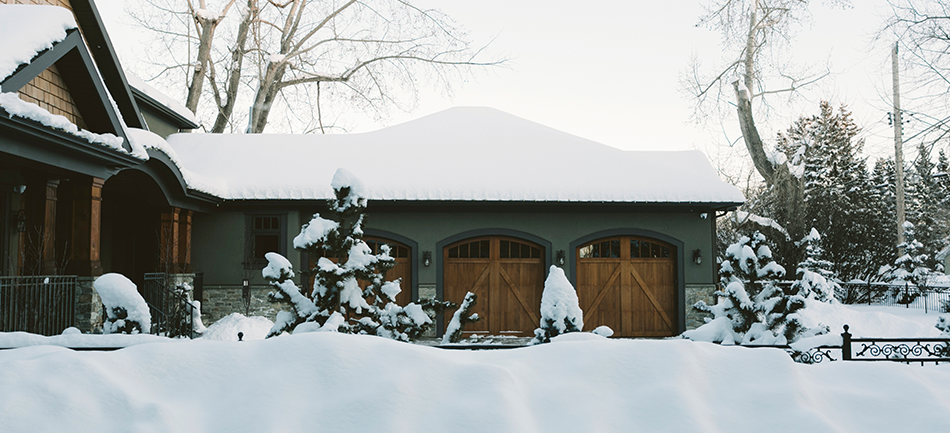 A house and driveway under deep fresh snow