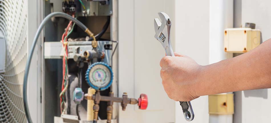 A technician adjusting a building's heating system with a wrench