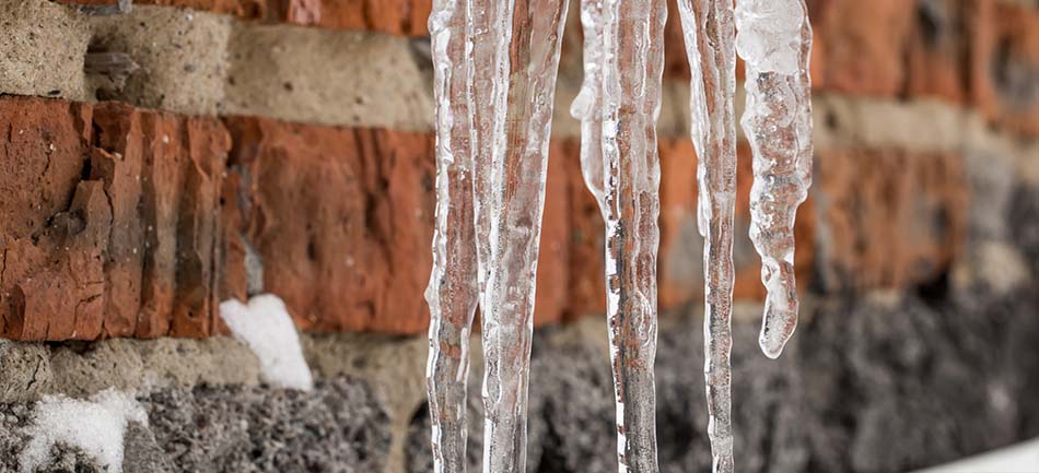 Icicles hanging against a brick wall