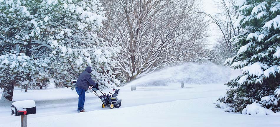 A person clearing a snowy path with a snow blower