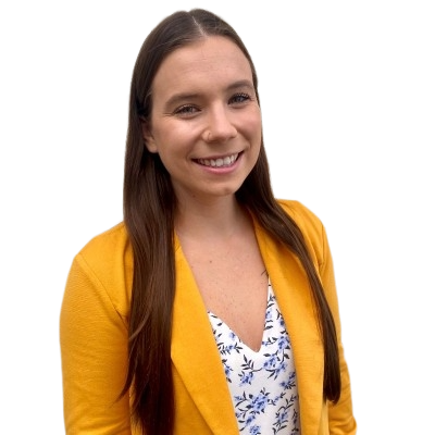 Smiling woman with long brown hair wearing a bright yellow blazer over a white blouse with blue floral patterns against a transparent background.