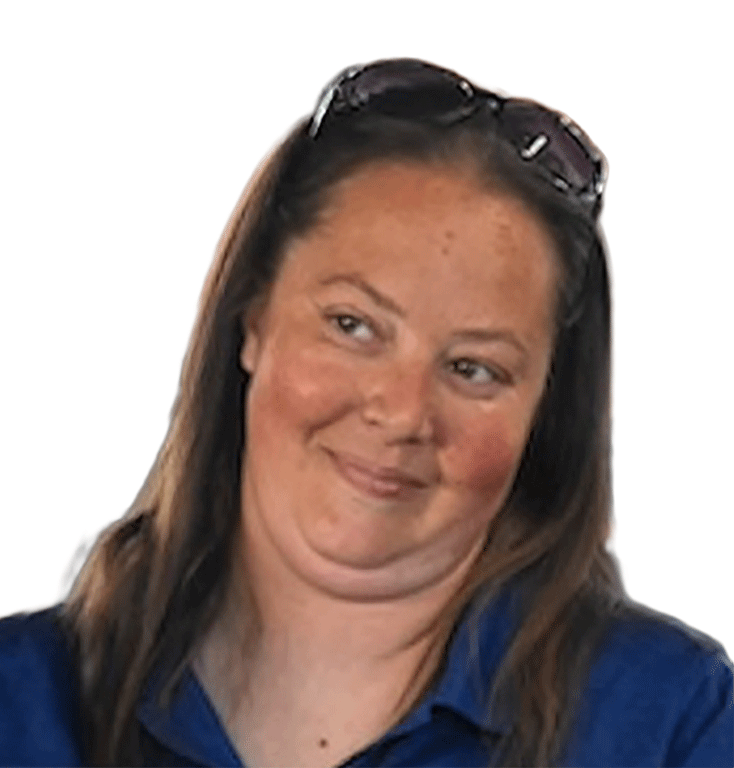 Woman with long brown hair wearing a blue shirt and sunglasses on her head, smiling with a slight smirk and looking to the side.