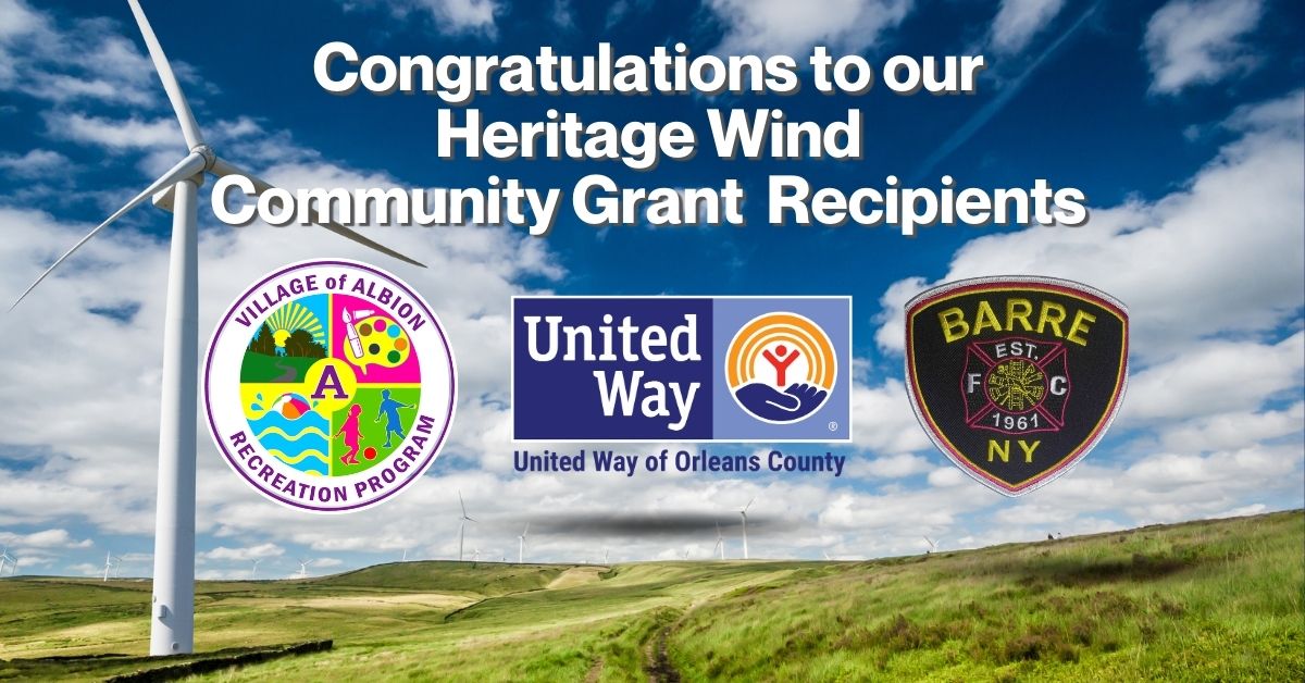 Wind turbines on a grassy landscape under a blue sky with clouds and text congratulating Heritage Wind Community Grant recipients accompanied by logos of Village of Albion Recreation Program, United Way of Orleans County, and Barre Fire Company.