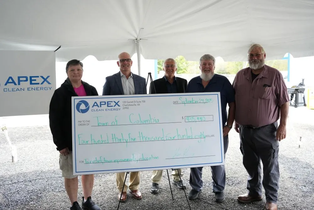 Five people standing under a tent holding a large check from Apex Clean Energy to Town of Columbia.