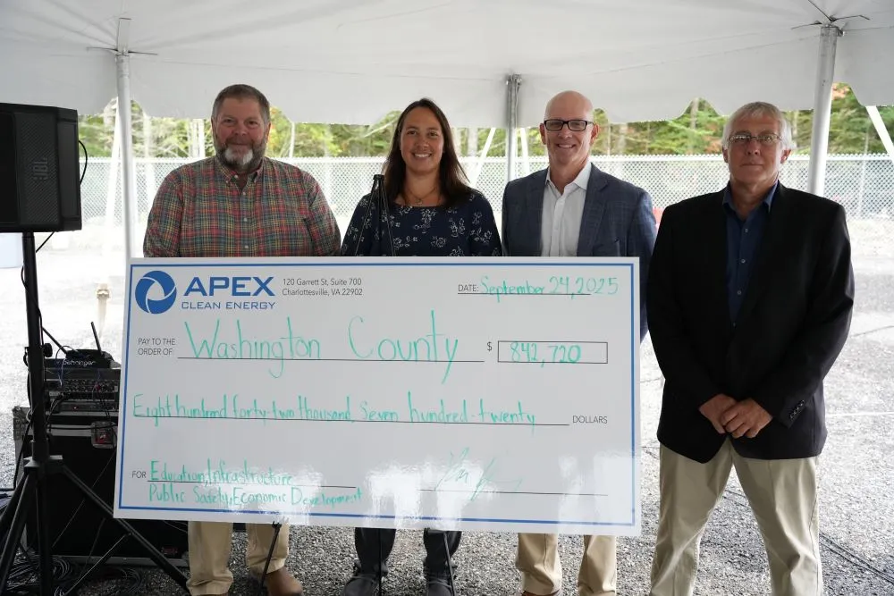 Four people holding a large Apex Clean Energy check for $842,720 payable to Washington County.
