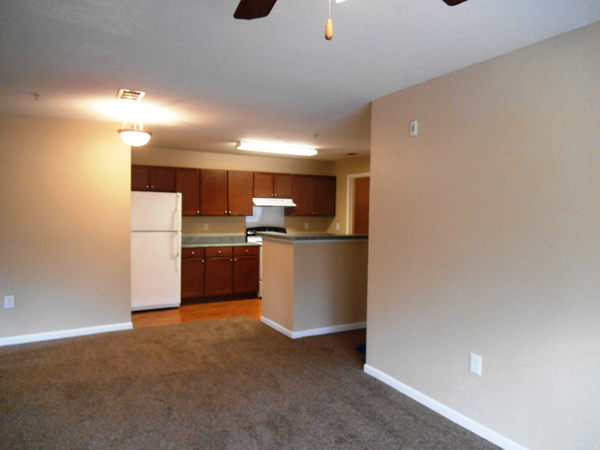 Empty living room with view of kitchen