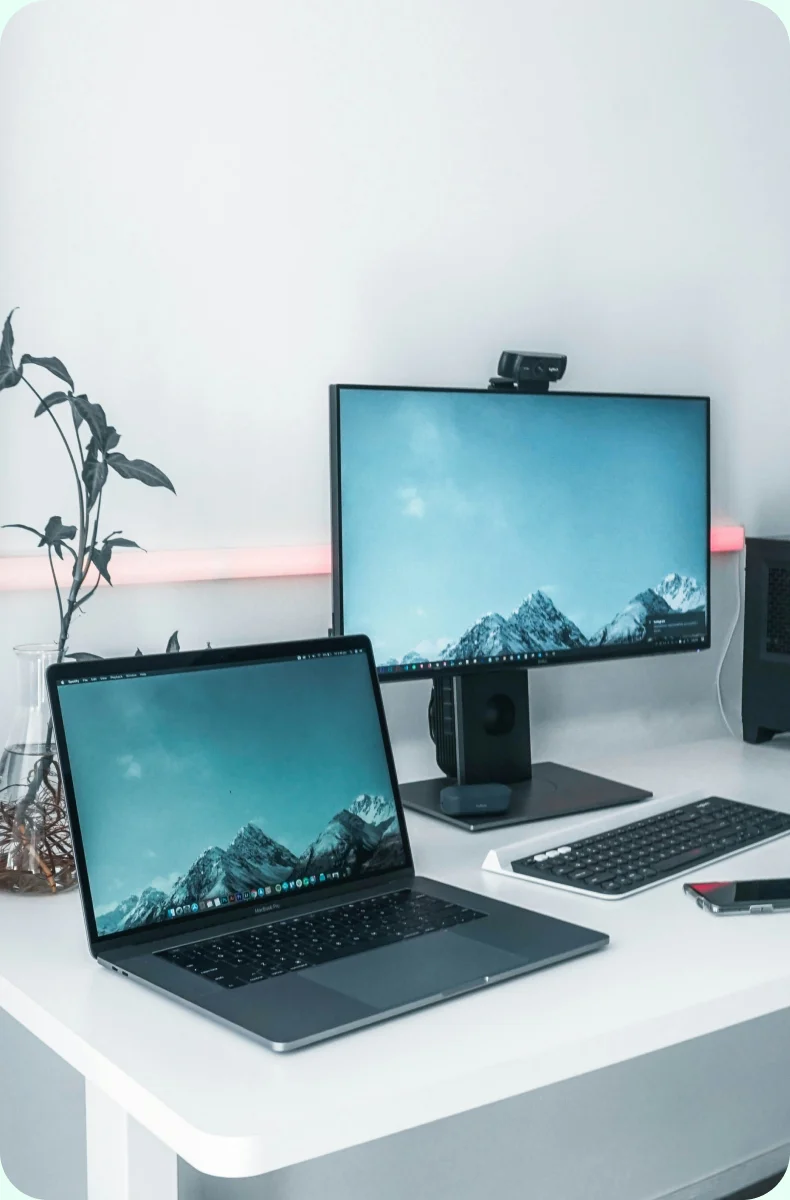 Office desk set up with a laptop, monitor, webcam and keyboard