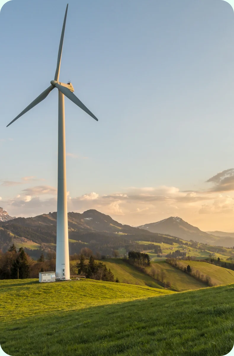 Wind turbine on a green hillside at sunset