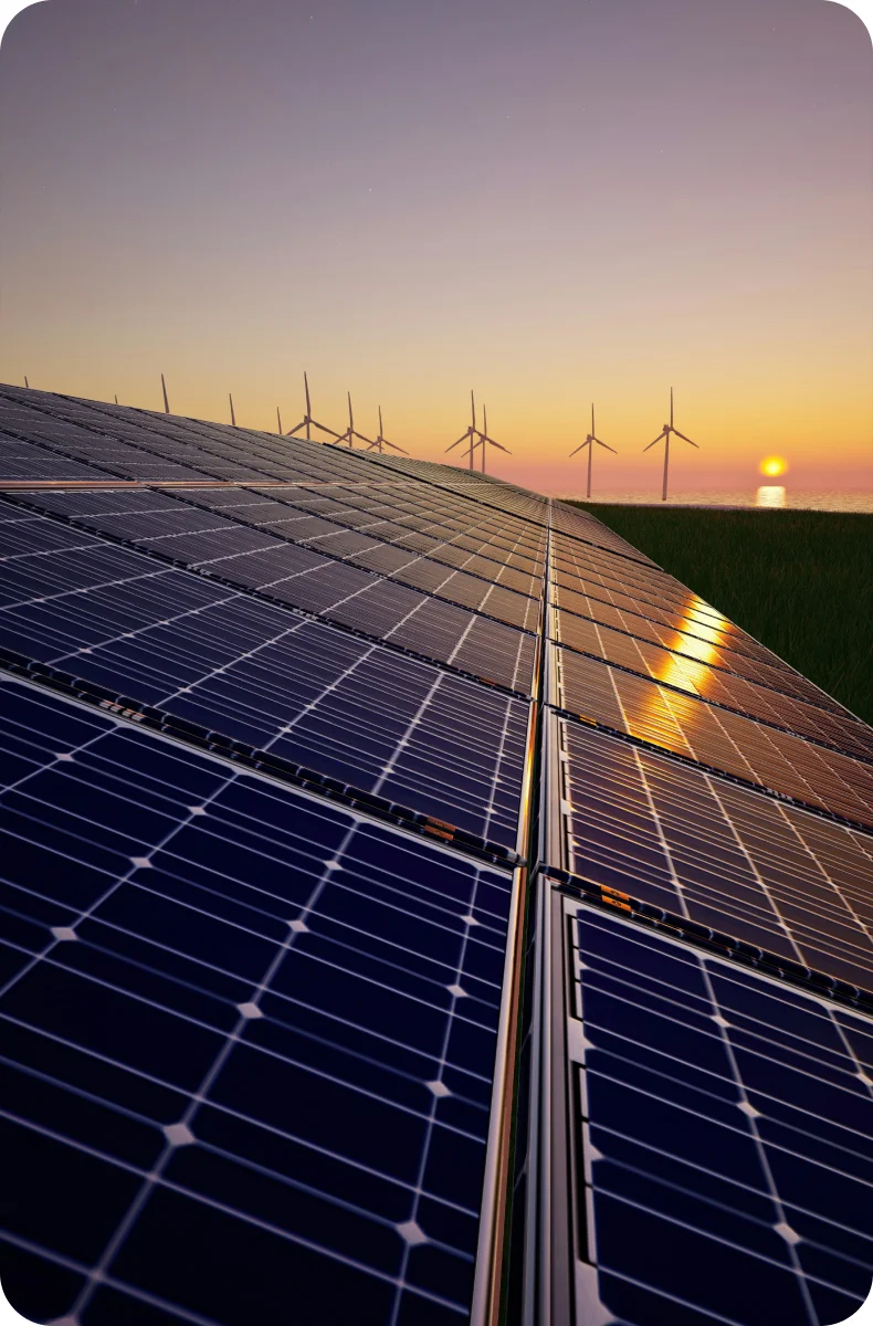 Rows of solar panels with wind turbines on the horizon at sunset