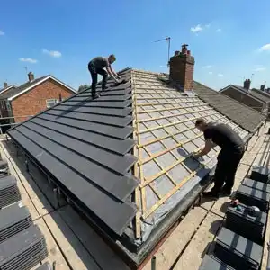 Roofer repairing damaged roof tiles on a pitched roof