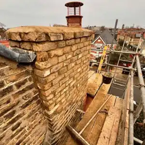 Brick chimney being repaired with new mortar and flashing