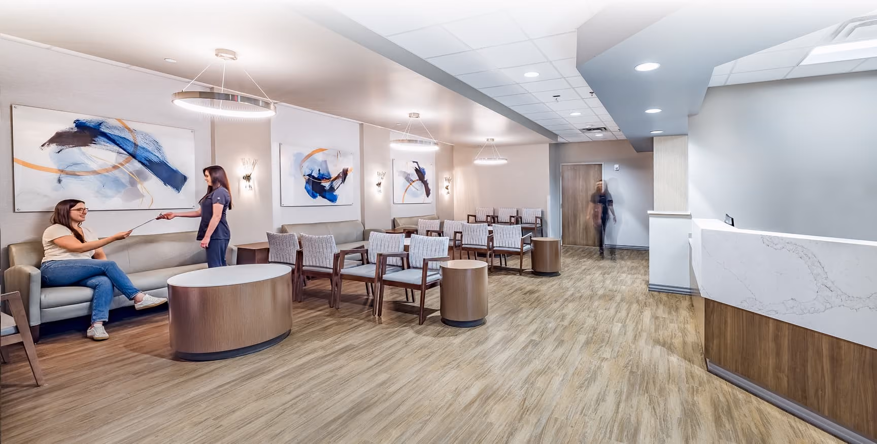 Northeast Digestive's modern gastroenterology office lobby with a staff member greeting a seated patient.