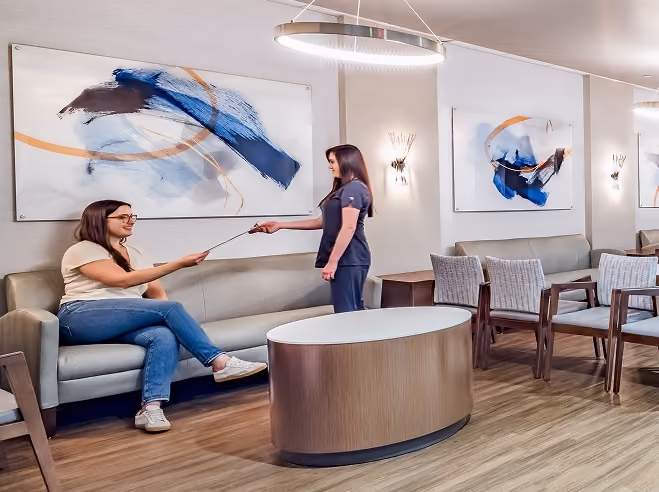 A staff member greeting a seated patient in Northeast Digestive's modern waiting room.