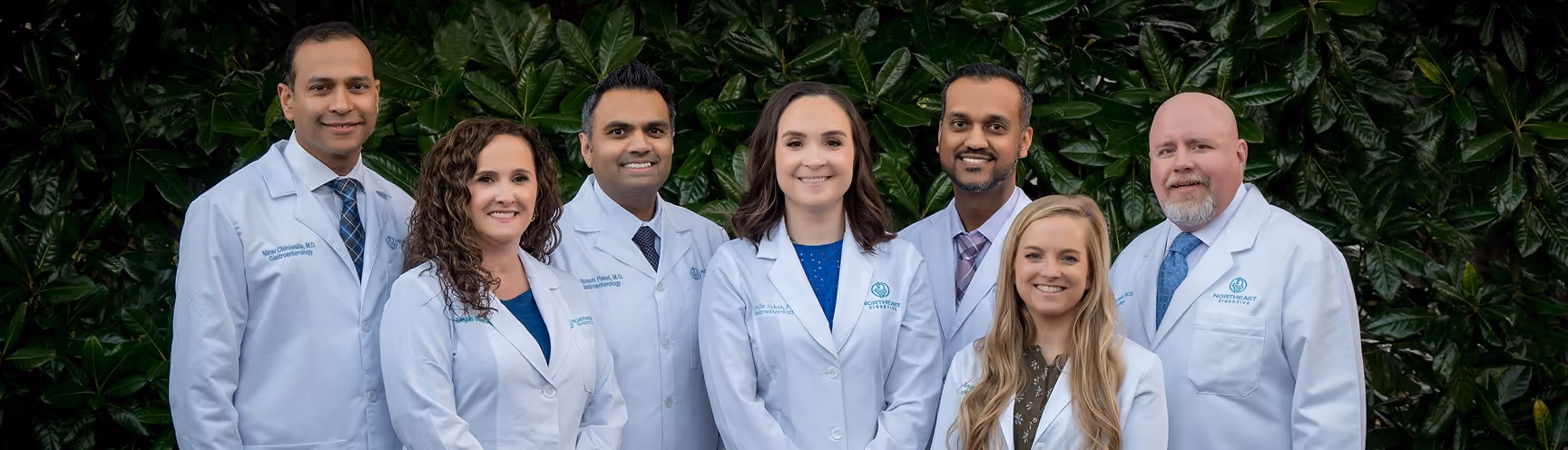 Seven Northeast Digestive gastroenterology providers in white coats posed together outdoors.