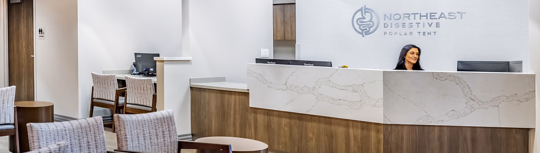 Front desk receptionist at Northeast Digestive's Poplar Tent office in Concord, NC, with waiting area seating.