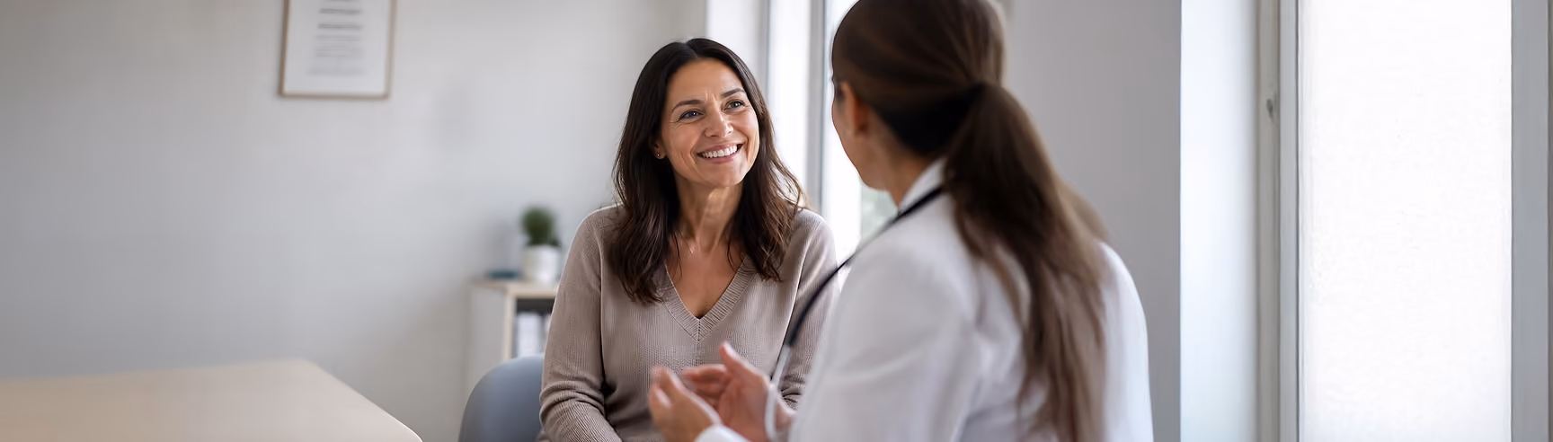 A smiling female patient in conversation with a Northeast Digestive female gastroenterologist during a Women's Wellness visit.