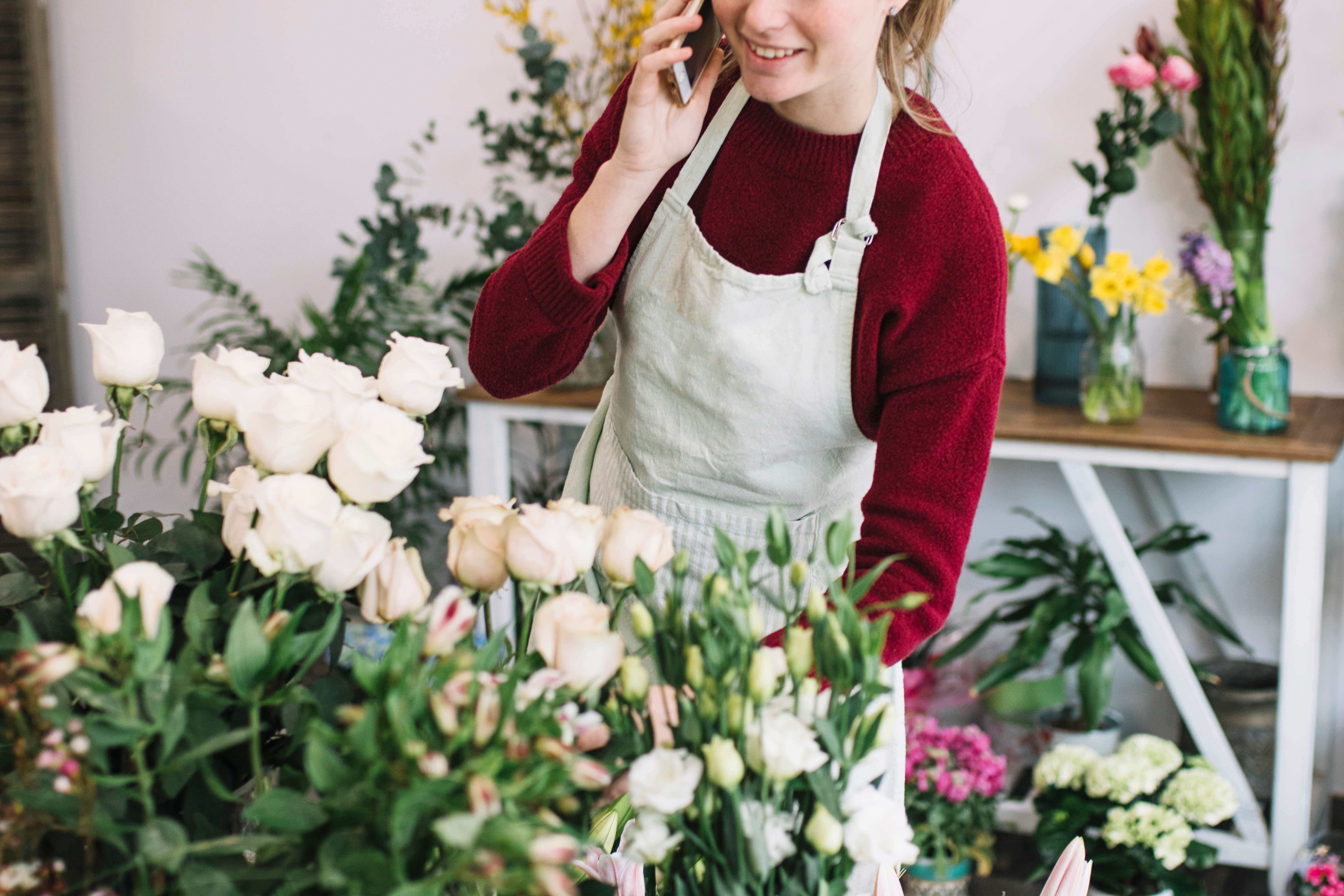 Florist taking an order by phone among fresh arrangements