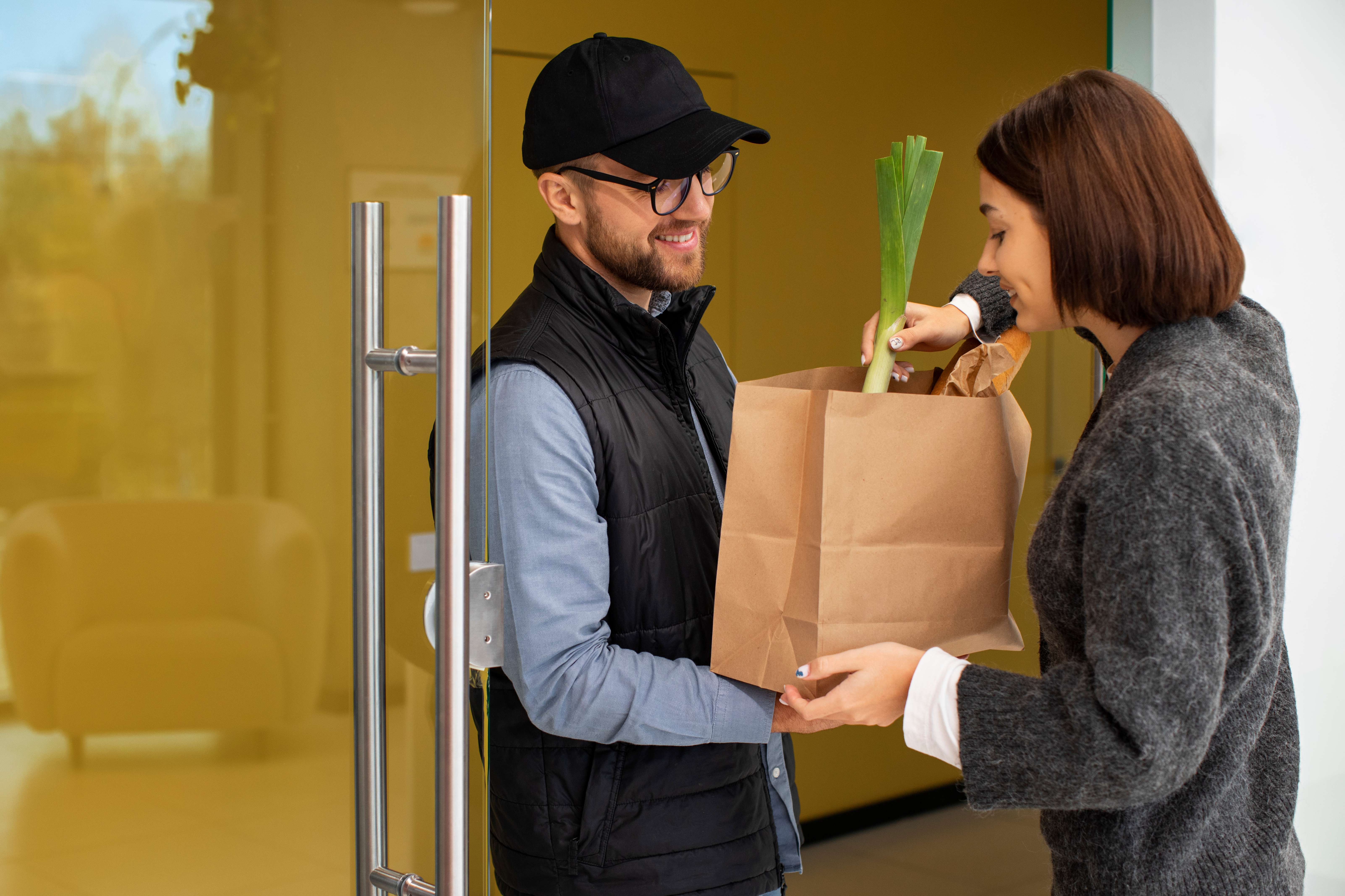Delivery driver handing a bag of groceries to a customer at the door