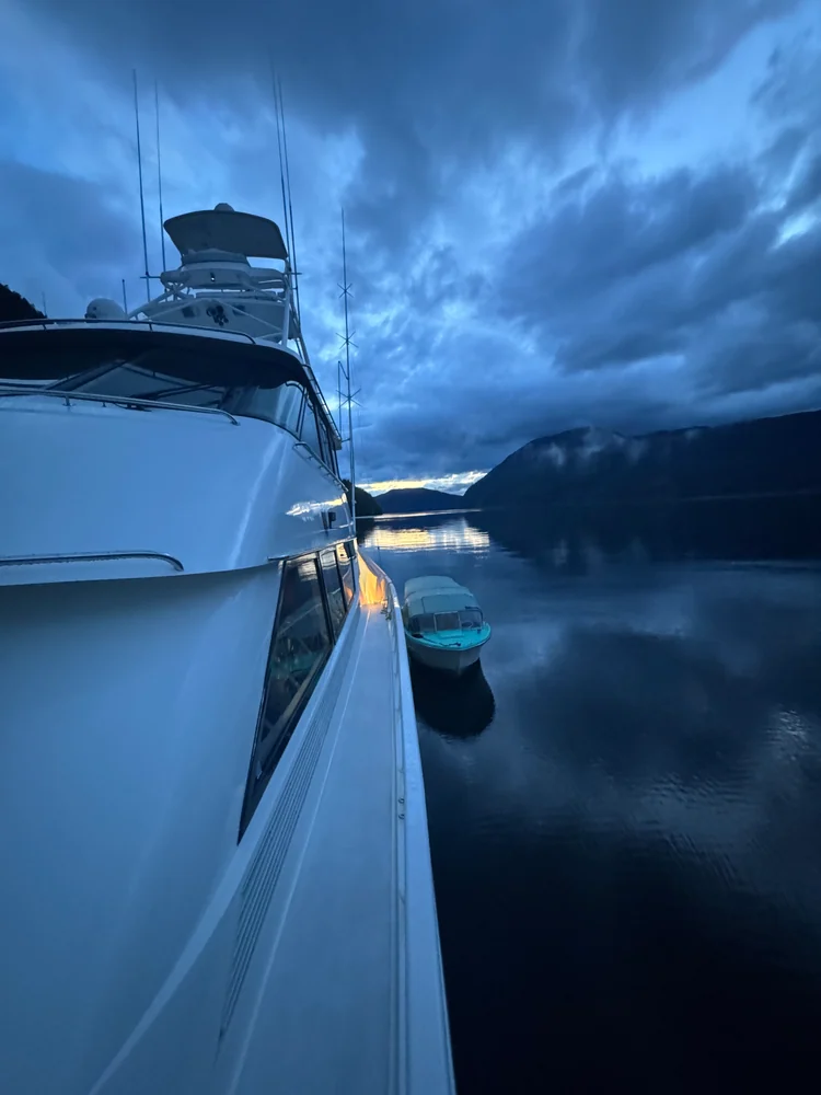 Close view of Surfrider's bow reflected in still water under a blue evening sky.