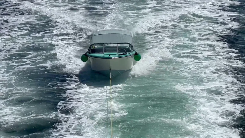 The turquoise-and-white family boat Seabird being towed in Surfrider's wake.