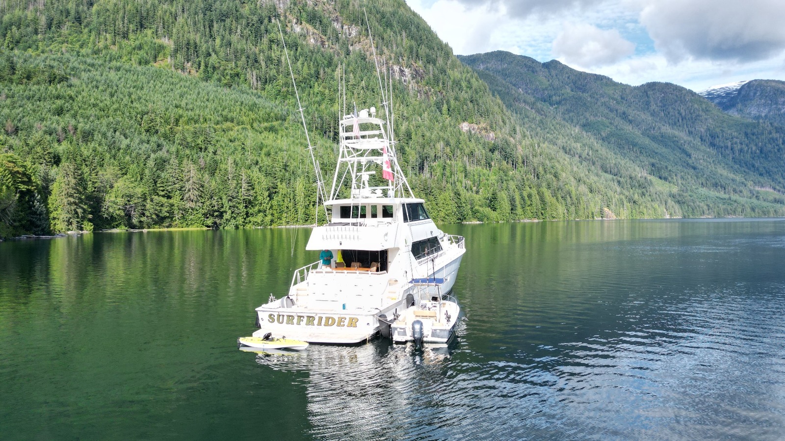 Stern view of Surfrider showing the cockpit, covered aft dining area and upper deck, with a smaller boat alongside
