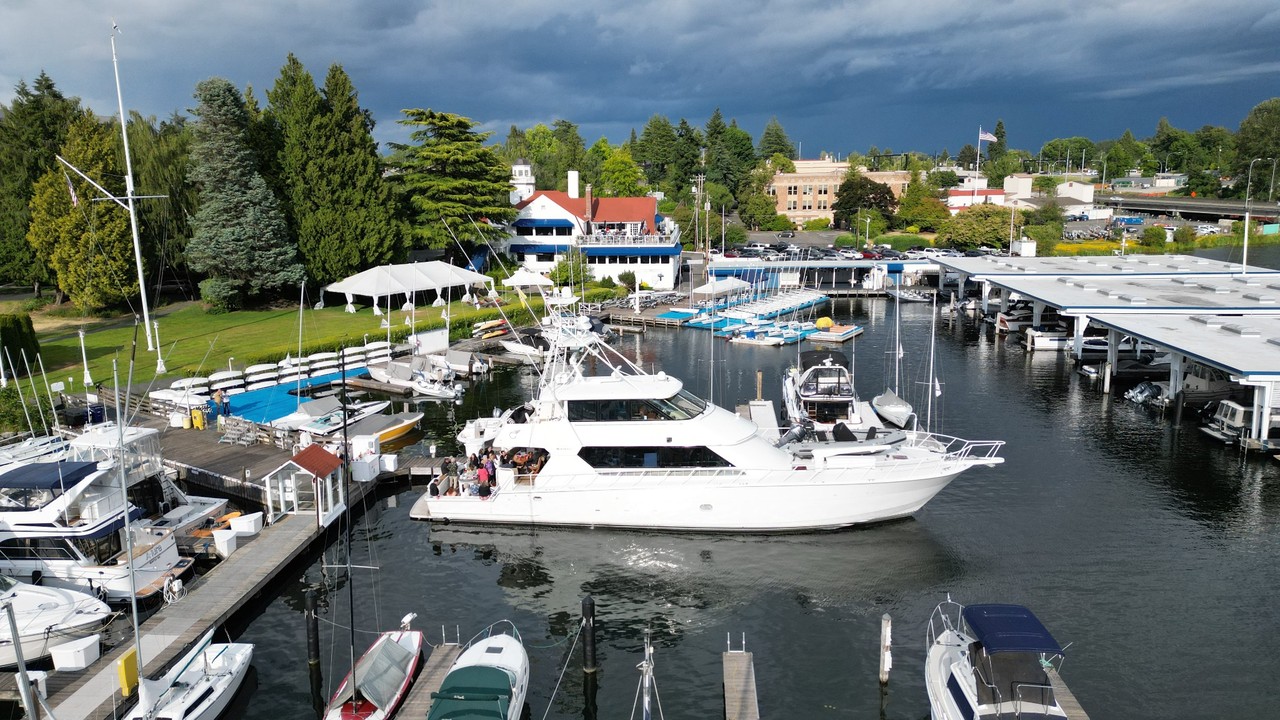 Surfrider beside a marina dock with people gathered on the aft deck