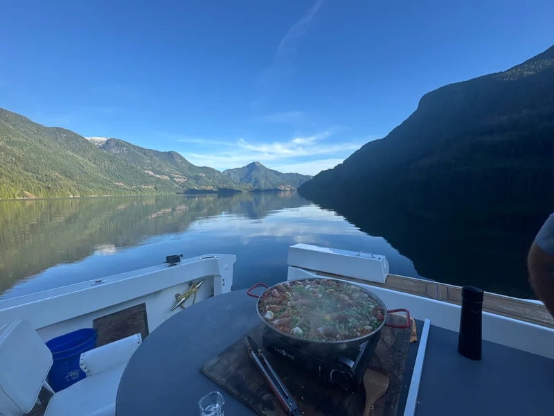 A pan on Surfrider's outdoor cooking surface, with calm water and mountains behind.