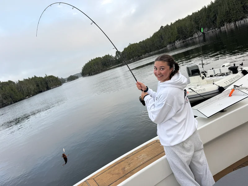 A smiling person holding a bent fishing rod at Surfrider's rail.