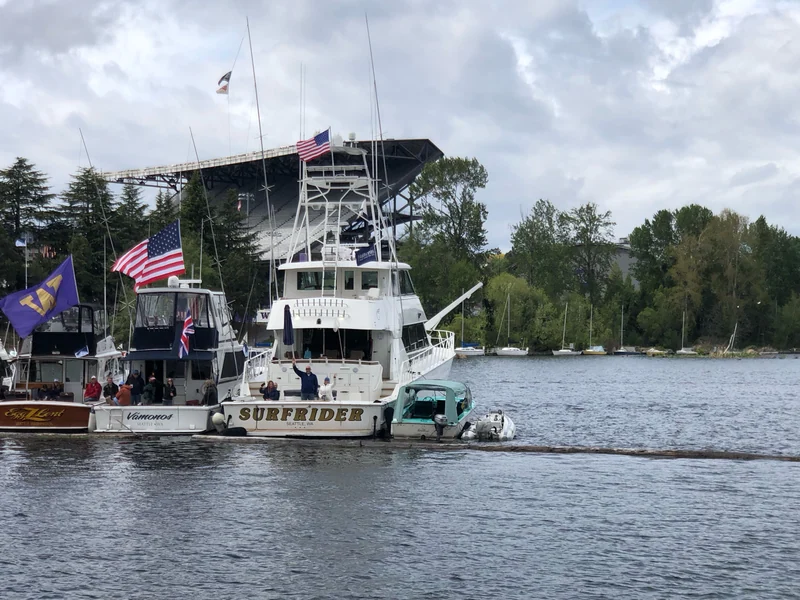 Surfrider on the water, with Husky Stadium and other boats in the background.