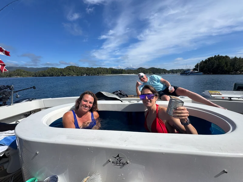 People relaxing in Surfrider's cockpit hot tub with blue water beyond.