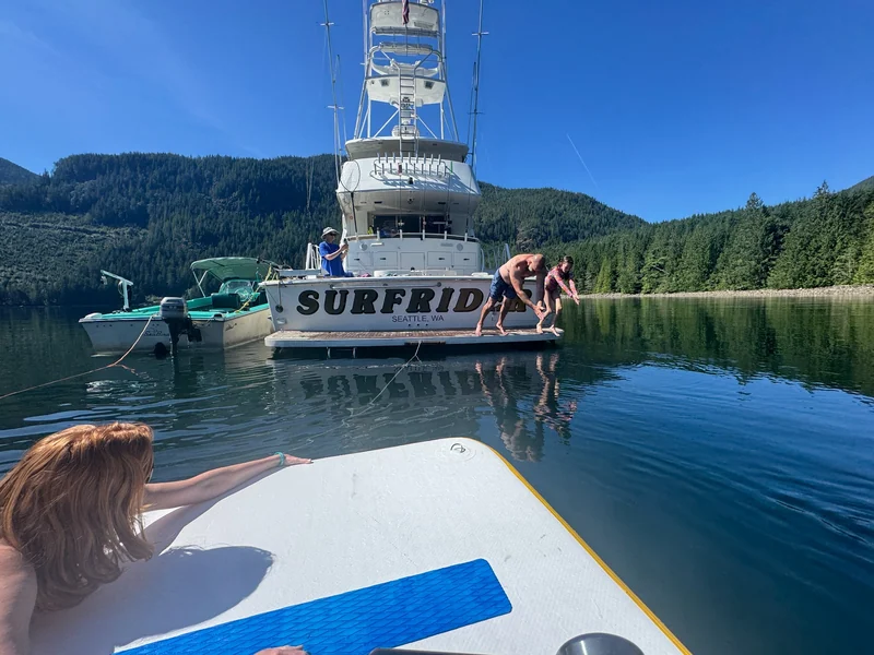 People by Surfrider's swim platform, photographed from a floating platform in a calm anchorage.