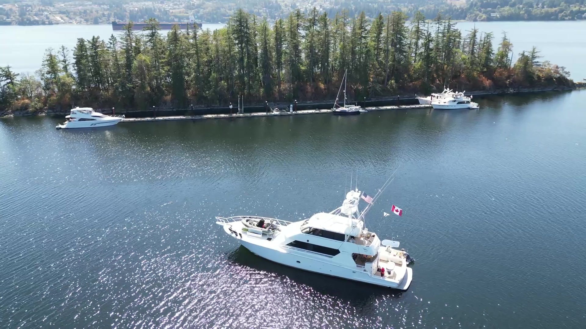 Aerial view of Surfrider at anchor off Ovens Island near Ladysmith, British Columbia, with wooded shoreline and docks beyond