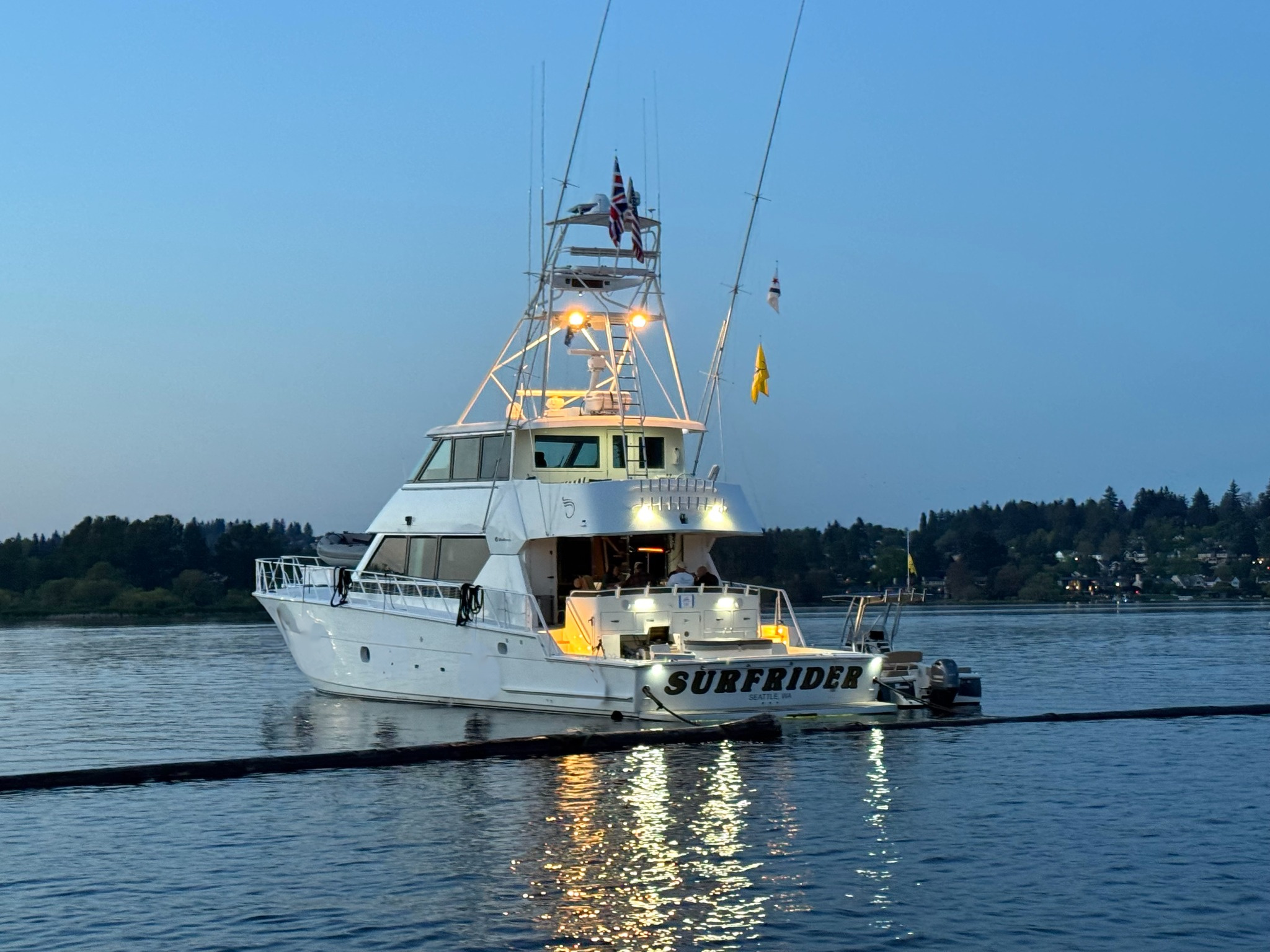 Surfrider at dusk, with the illuminated stern and yacht name visible