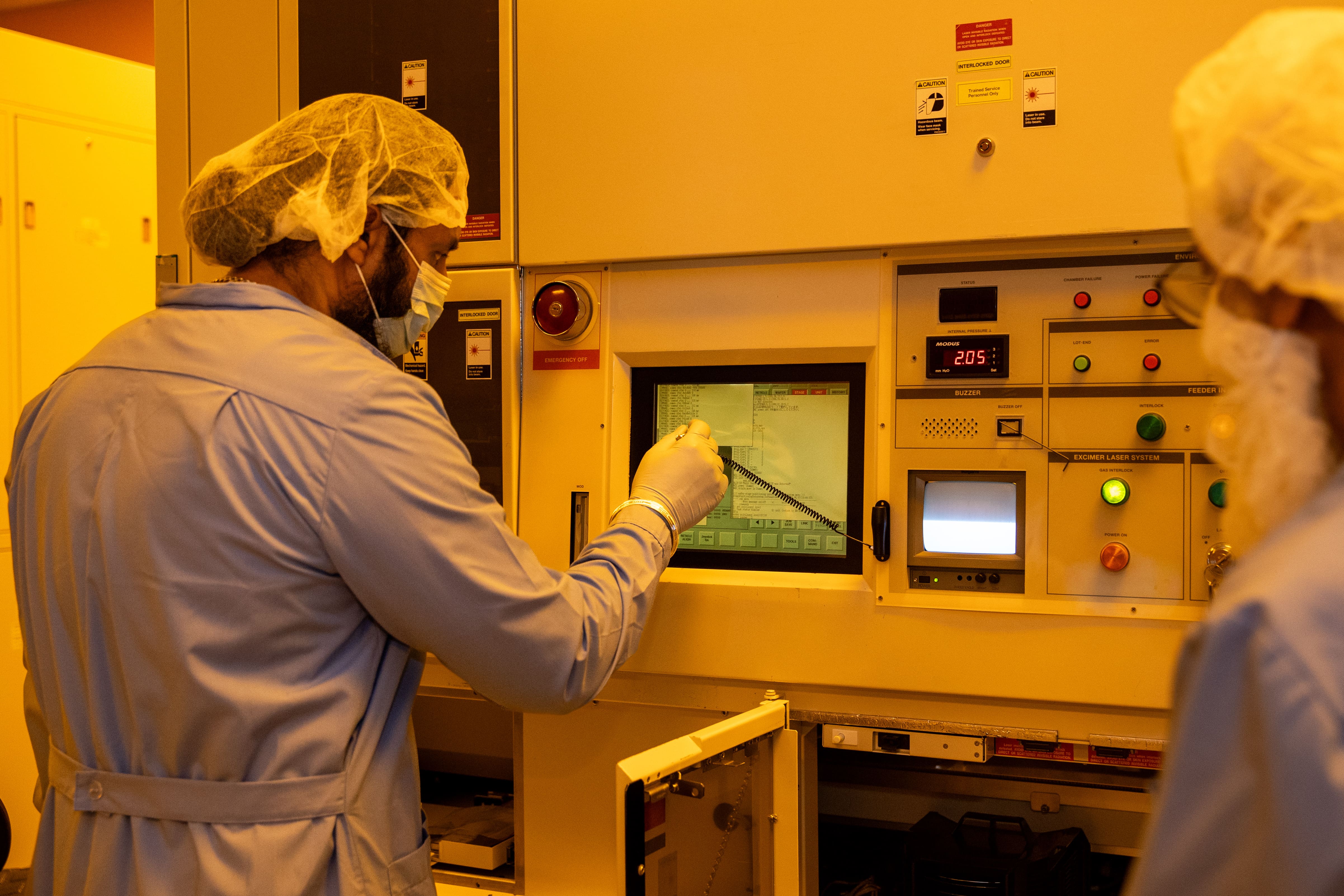 GCE engineer inspecting a wafer under a microscope in a cleanroom