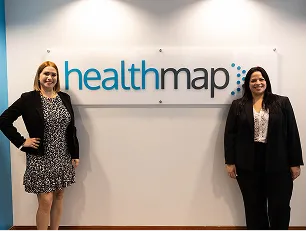 Two team members standing beside the Healthmap office sign.