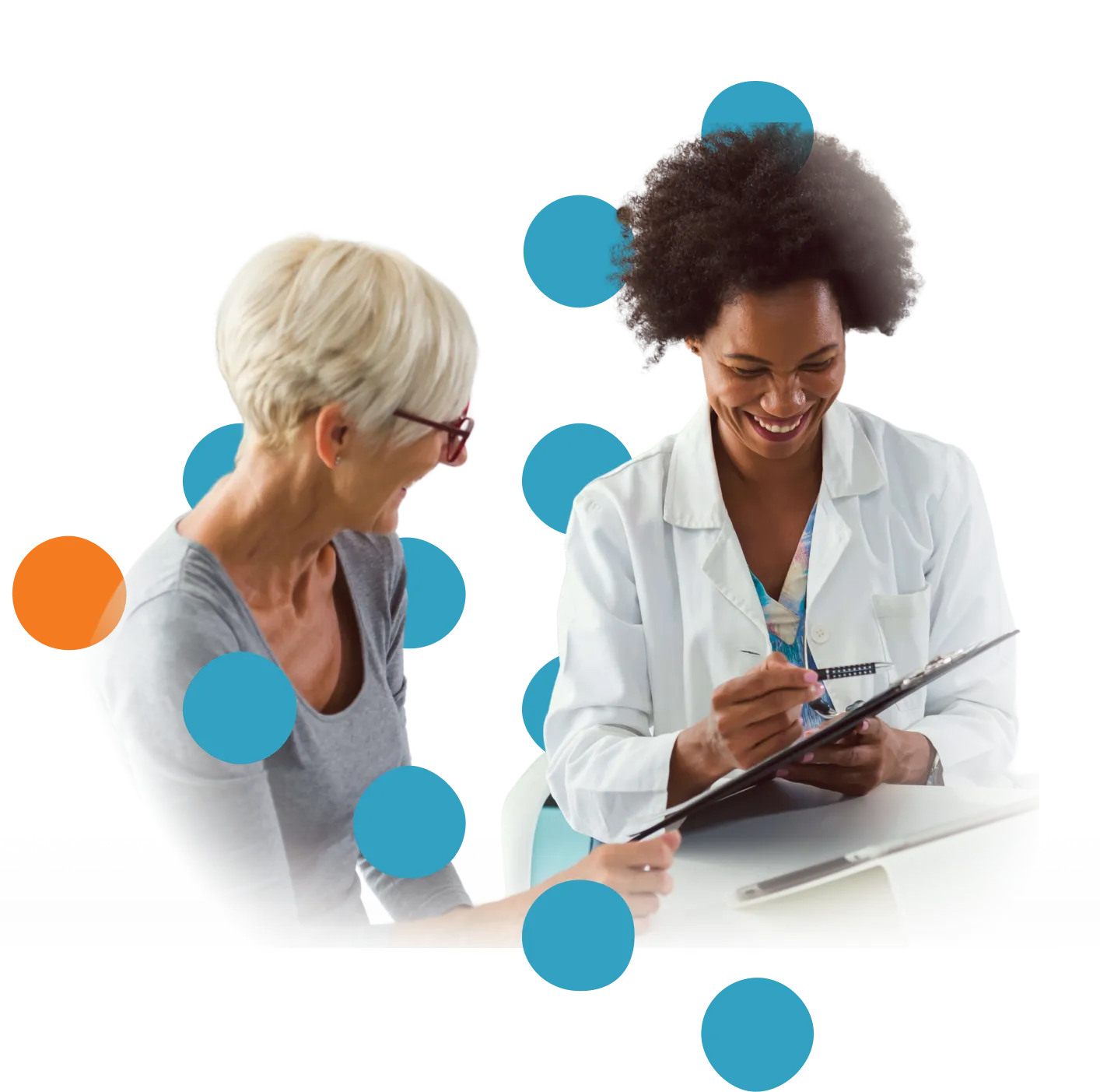 Smiling female doctor with curly hair in white coat reviewing a clipboard while talking to an older woman with short blonde hair and glasses, both engaged and happy in a medical consultation.