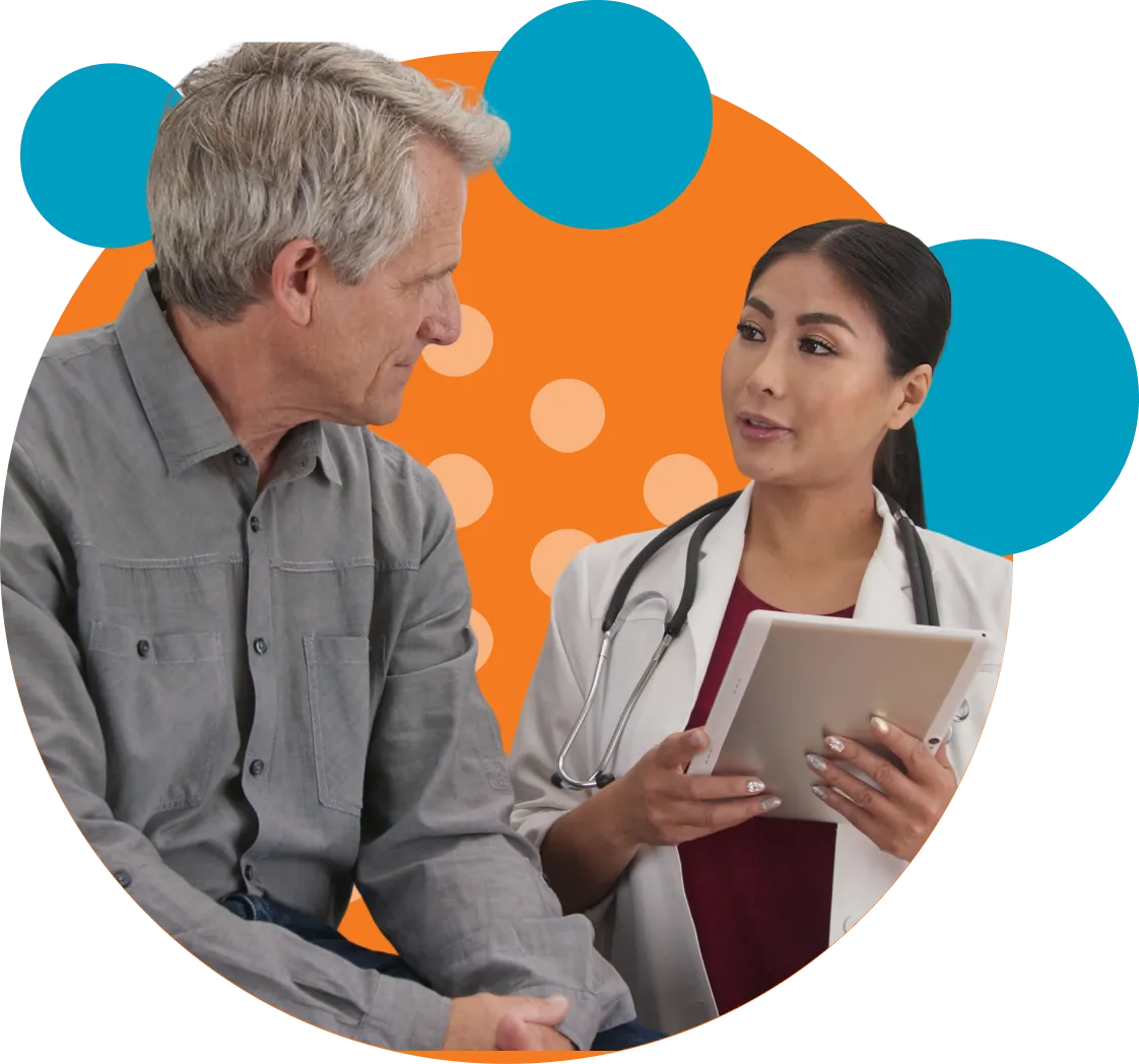 A female doctor in a white coat with a stethoscope around her neck holds a tablet and talks to an older male patient wearing a gray button-up shirt against an abstract background with orange and blue circles.