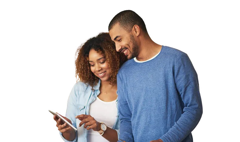 A smiling woman with curly hair wearing a light denim shirt and a man with short hair and beard in a blue sweater looking at a tablet together.