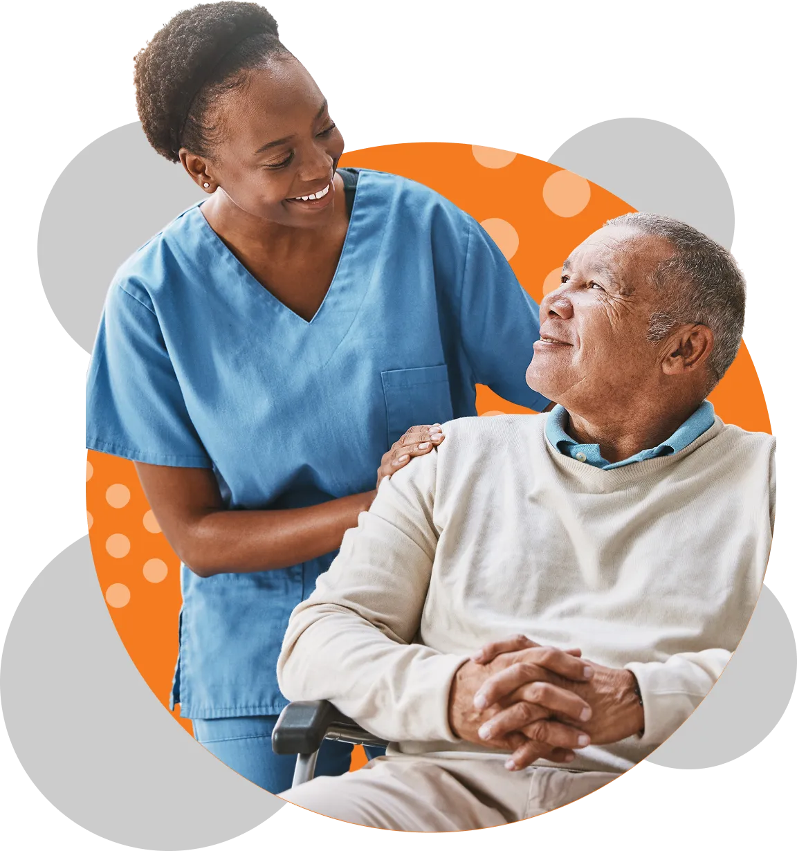 A female healthcare worker in blue scrubs smiles warmly while placing her hand on the shoulder of a seated elderly man who looks up at her with a gentle smile.