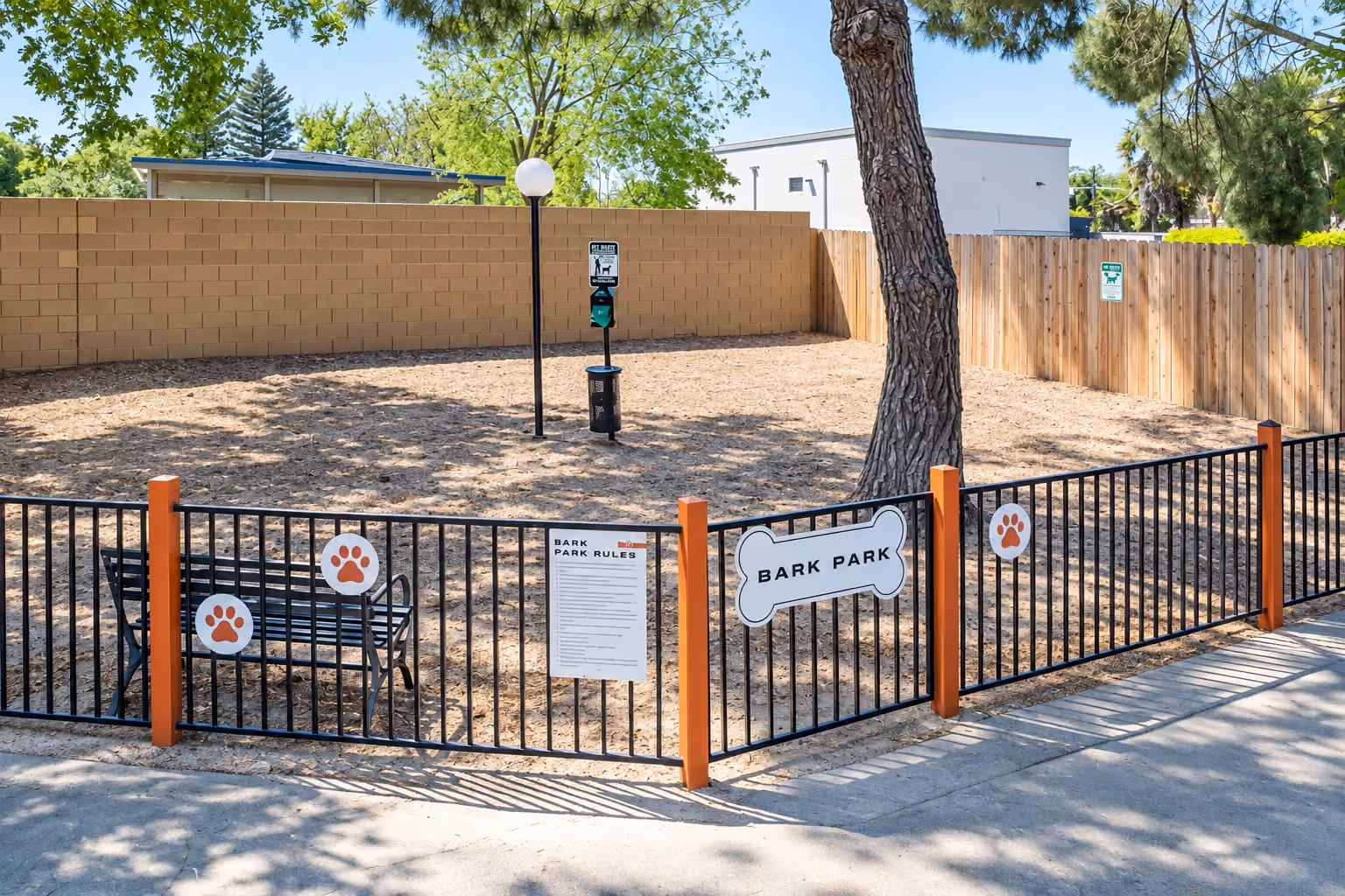 Fenced in dog park with sand and mulch.