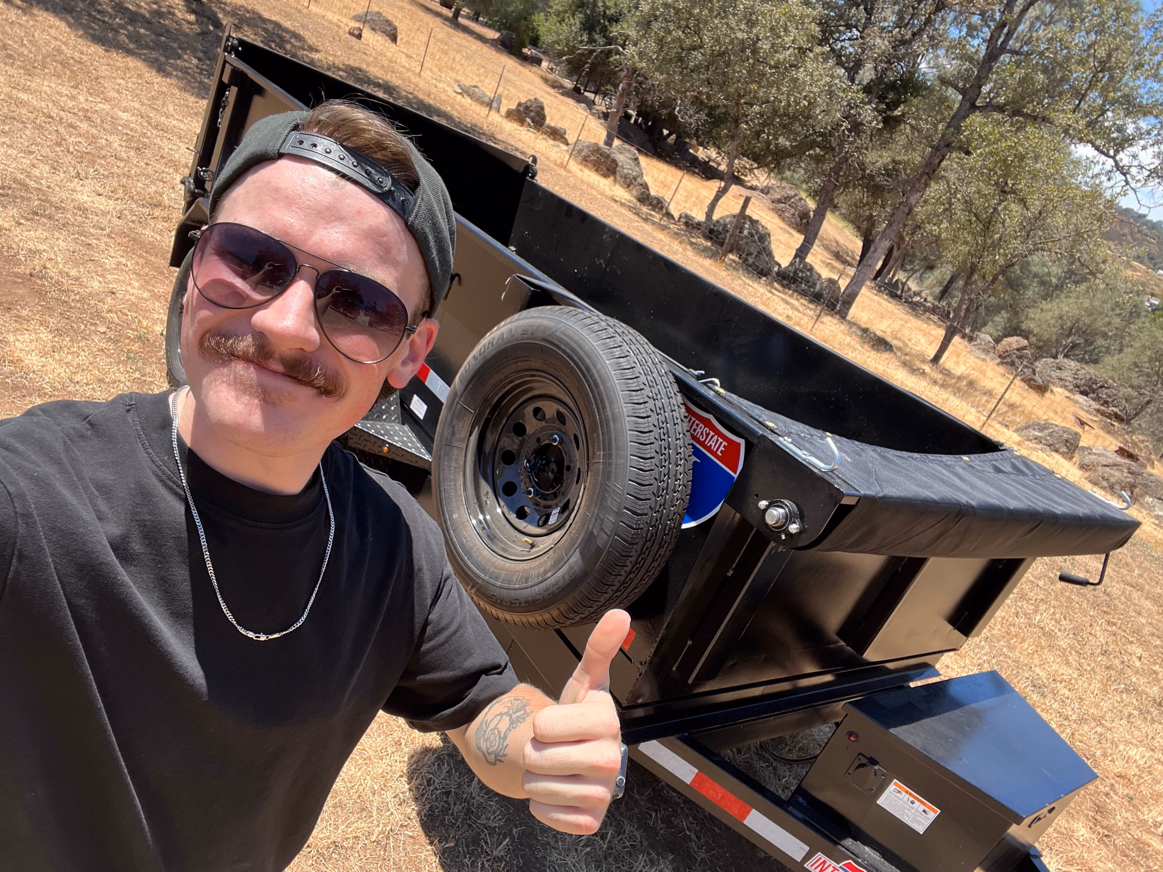 Aidan with the ATS dump trailer parked on an oak-covered property