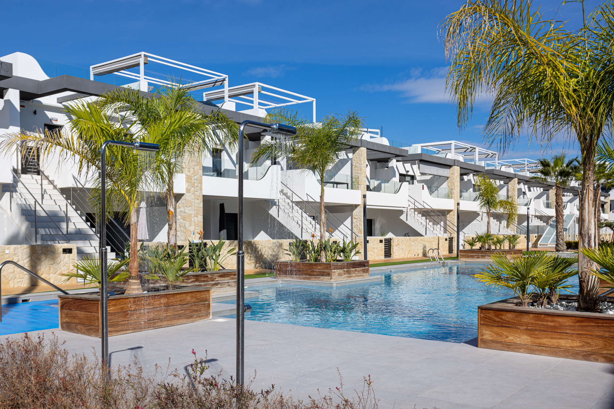 Gemeenschappelijk zwembad en palmentuinen onder de appartementen van Innova Beach, Orihuela Costa, de thuisbasis van Casa Jordino