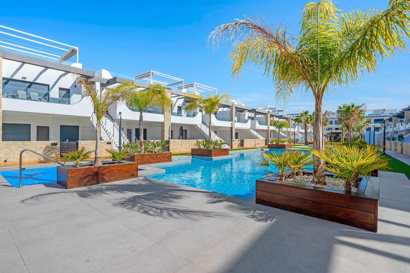 Pool and palm trees between townhouses on the Costa Blanca in full sun